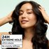 A woman with voluminous, dark wavy hair smiling. An overlay box reads "24H EXTREME HOLD" and "No crunchy stiffness".