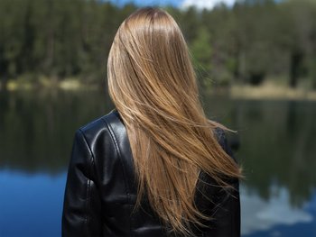 The back of a person's head showcasing medium-length, light brown hair, described as a neutral tone for first-time colorers.