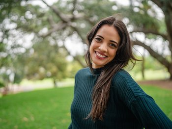 A woman with warm skin and soft black hair smiles.