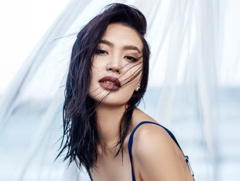 A woman with reflective blue-black hair smiles, showcasing the blue tones in her hair.