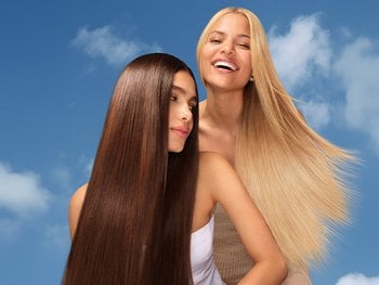 Two women with long, shiny, and healthy hair – one with smooth dark brown hair and the other with flowing blonde hair – showcasing the results of effective hair care products.