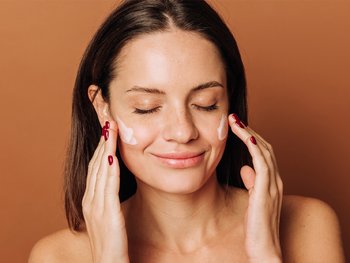 A person applying coconut oil to their skin.