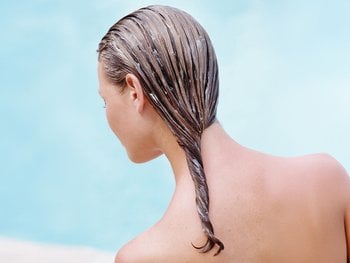 The back of a person's head is shown with wet hair treated with coconut water as a leave-in conditioner.