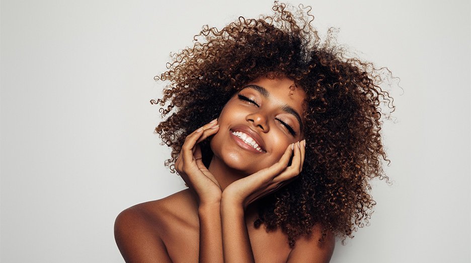 Smiling woman with voluminous curly hair.