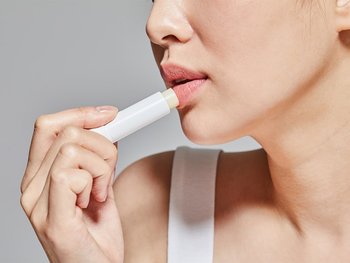 A person applying shea butter to their lips.