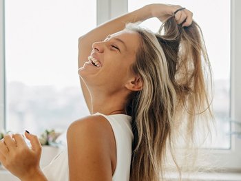 Women with blonde hair combing with her fingers.