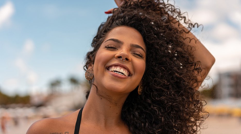 Portrait of woman long 3B curly hair, smiling at the camera.