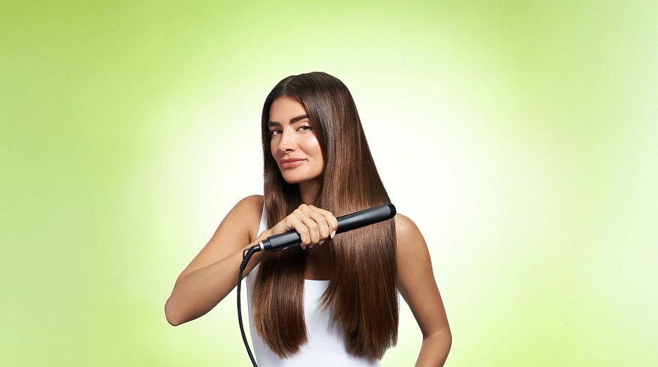 Brunette model facing forward as she straighten long, thick, smooth hair.