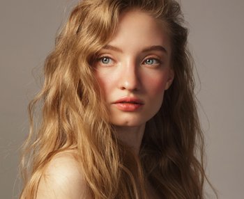 Model with red wavy hair posing in front of the camera.