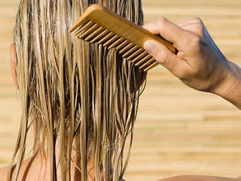 A close-up of wet hair being combed.