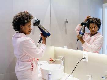 Woman blow drying hair with a diffuser.