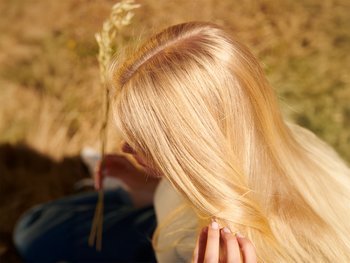 Close up of a woman applying hair product.