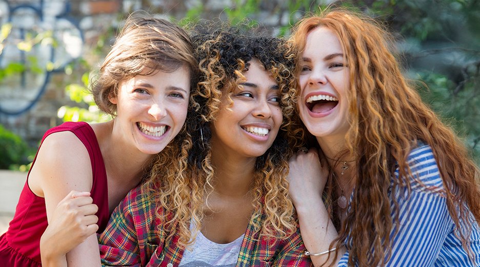 Group of women with different curl types hugging.