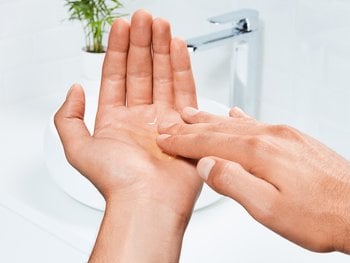 A close-up of hands holding a small amount of clear shampoo.