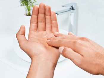 A close-up of hands holding a small amount of clear shampoo.