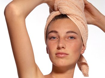 A woman wraps her hair in a towel after washing.