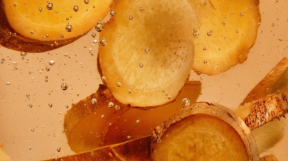 Close up of ginger slices submerged in a liquid substance.
