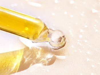 A close-up of a dropper dispensing biotin oil.