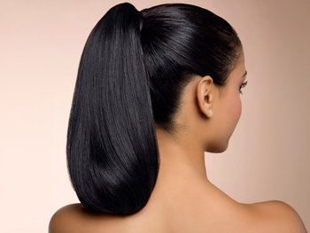 A view of a woman’s thick and voluminous ponytail, highlighting the increased hair shine that biotin can support.
