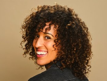 Woman with medium-length, curly hair, smiling.