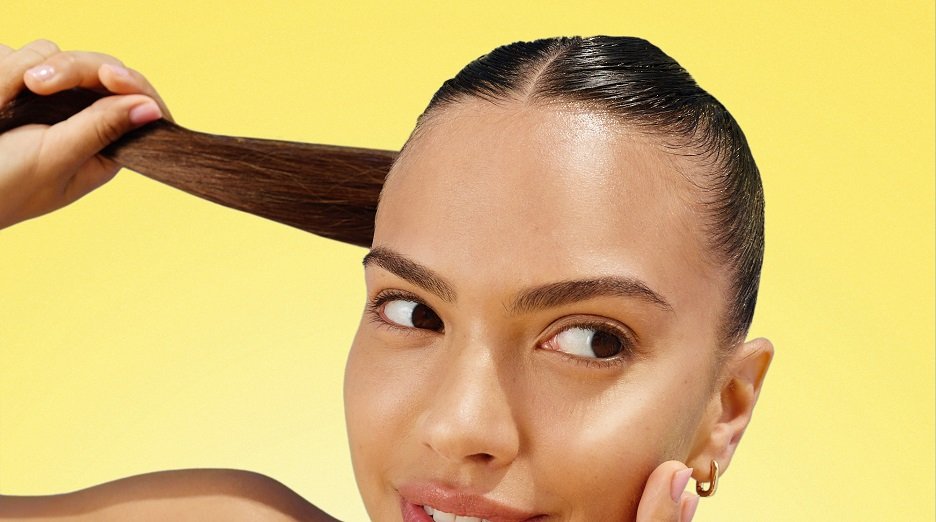 A woman examining her healthy, shiny hair, highlighting the benefits of vitamin C for hair care.