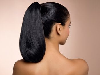 The back of a woman with long, sleek, black hair pulled into a high ponytail, set against a warm, light brown background.