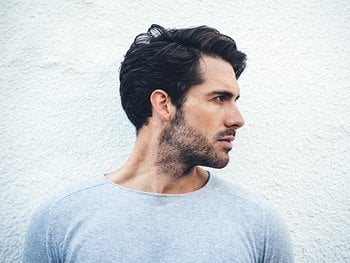 Serious portrait of a young man portraying a side part hairstyle.