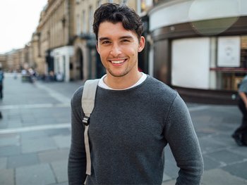 Happy young man in the city featuring a messy look hairstyle.