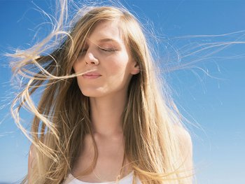 Blonde woman whose hair is blowing in the wind outside