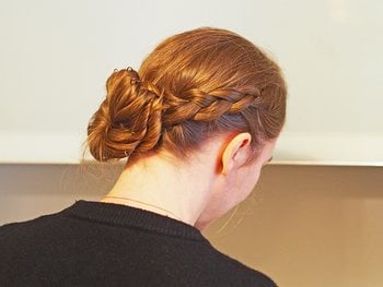 A woman with braided sides and wavy, medium-length hair styled in a half-up, half-down do.