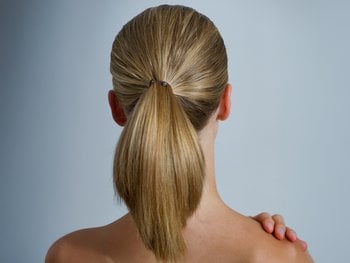 The back of a woman's head showcases a neatly styled high ponytail.