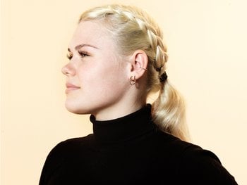 A profile view of a woman with blonde hair styled into a French braid leading into a ponytail.