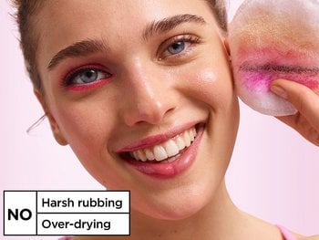 Smiling woman holding a makeup pad with removed makeup, demonstrating that Garnier Micellar Water involves no harsh rubbing and no over-drying.