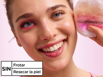 Smiling woman holding a makeup pad with removed makeup, demonstrating that Garnier Micellar Water involves no harsh rubbing and no over-drying.