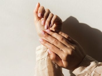 A hand applies a white cream to another hand, depicting the application of a targeted dark spot treatment.