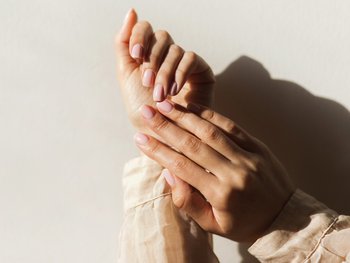 A hand applies a white cream to another hand, depicting the application of a targeted dark spot treatment.