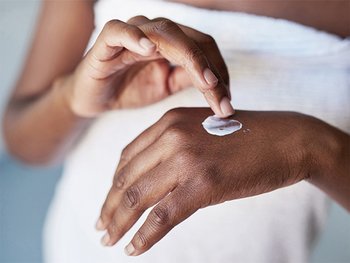 A woman applying a cream to moisturize.
