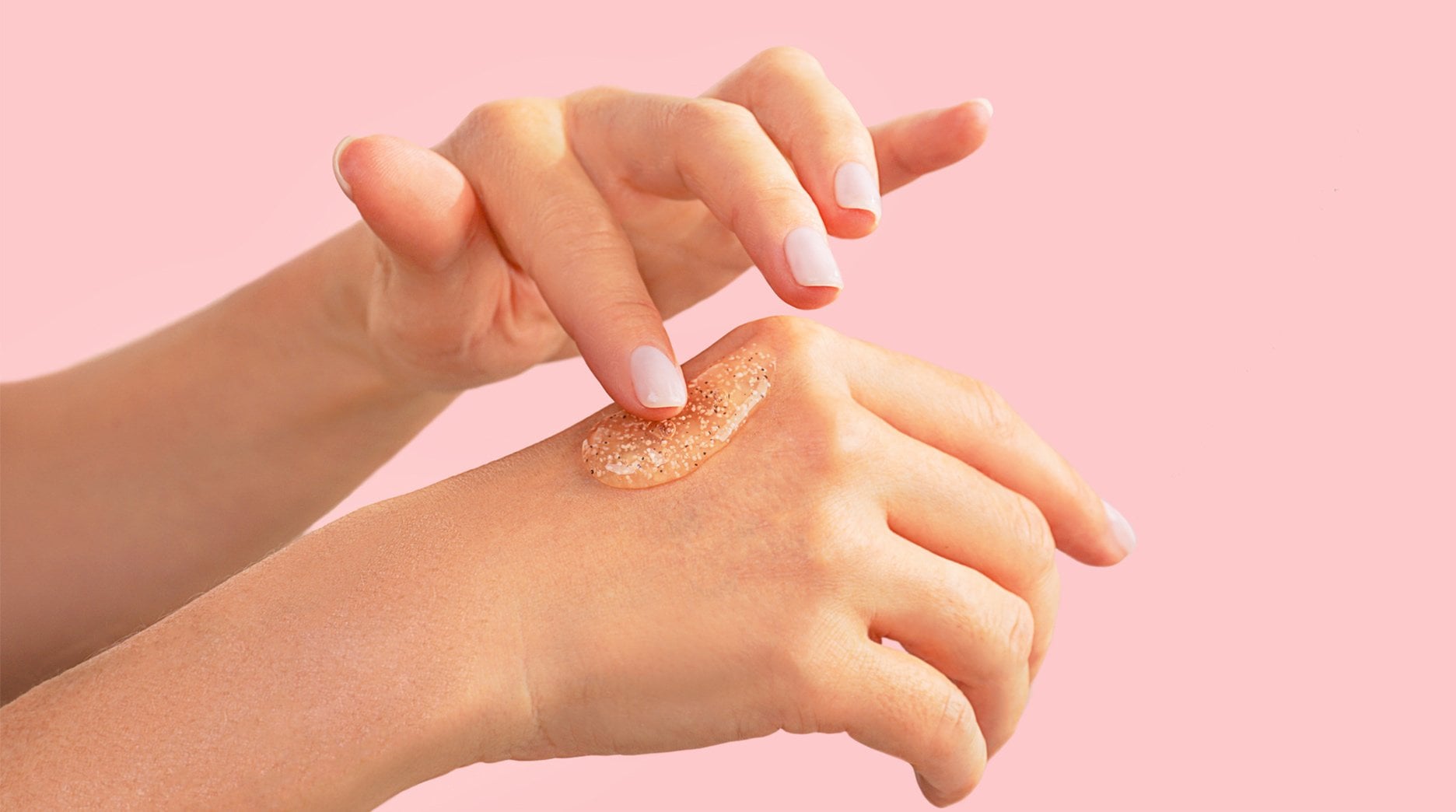 A hand applies a translucent, gel-like substance to the back of another hand.
