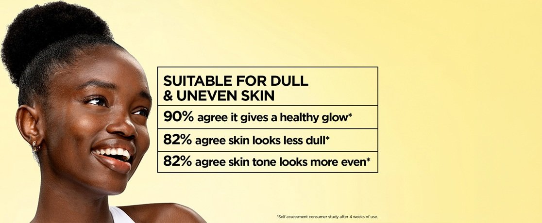 Garnier Micellar Vitamin C skincare hero banner featuring a smiling dark-skinned woman with her coily hair styled in a high bun, glowing even-toned skin, and a white top against a soft yellow background, alongside a bold black-outlined text box on cream stating "Suitable for Dull & Uneven Skin" with consumer study results showing 90% report a healthy glow, 82% agree skin looks less dull, and 82% agree skin tone looks more even after 4 weeks of use.