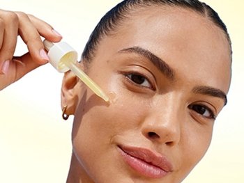 Close up of model applying serum to her cheek.