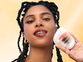 Model holding up used cotton pad showcasing the makeup she had on.