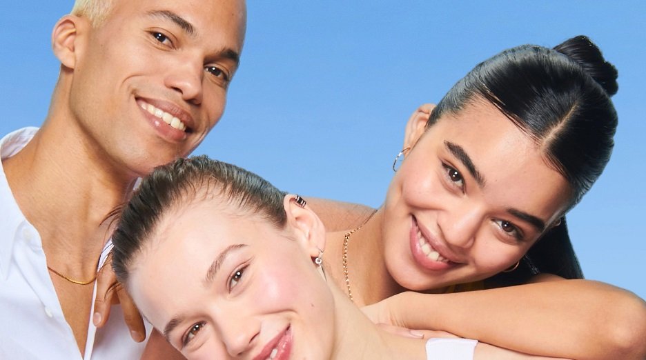 Group shot of diverse models, one blonde male and two brunette models, all with clear skin.