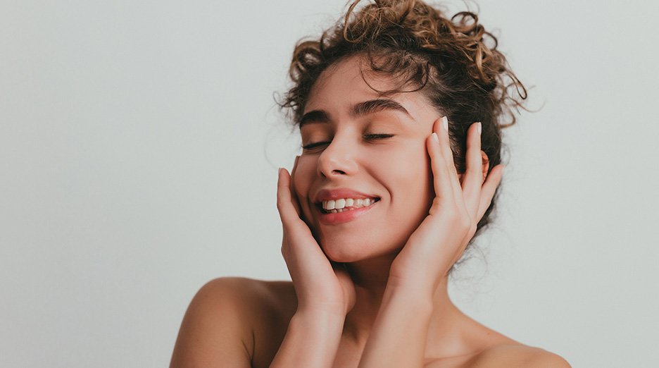 Smiling young woman with curly hear and clear skin