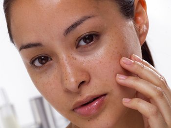 Front, close-up shot of woman gently touching her soft face.