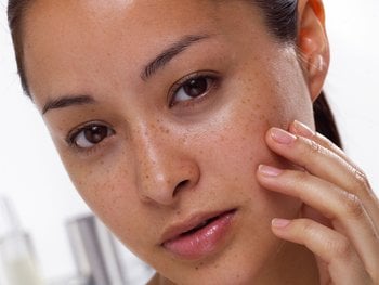 Front, close-up shot of woman gently touching her soft face.