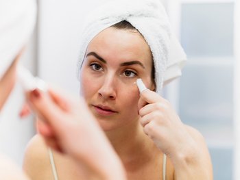 A person applies an eye roller to their under-eye area.