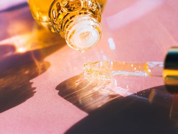 An amber-colored bottle dispenses a drop of serum.
