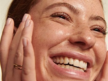 Woman smiling and touching her face.