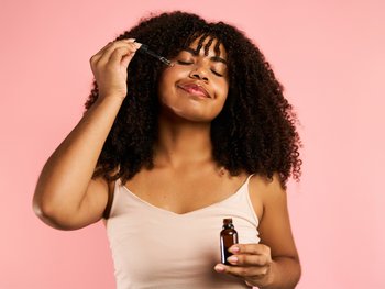 Woman applying serum to her face.