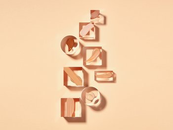 Abstract swatches of BB cream in various shades are arranged on a light orange background.